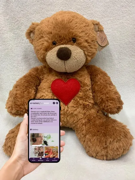 eMemorybear with a phone held in front showing a memorial page in the app