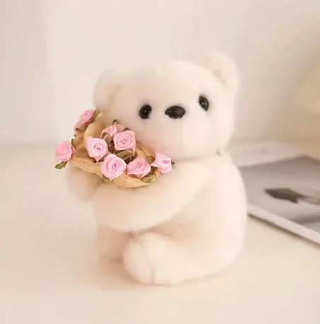 Small cream teddy bear holding a bouquet of pink roses