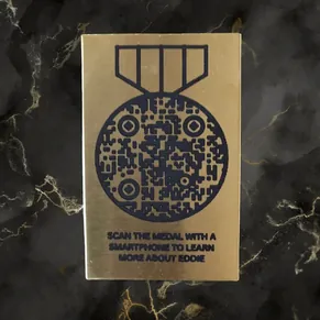 Brass memorial plaque with a medal-shaped QR code: scan the medal with a smartphone to learn more about Eddie